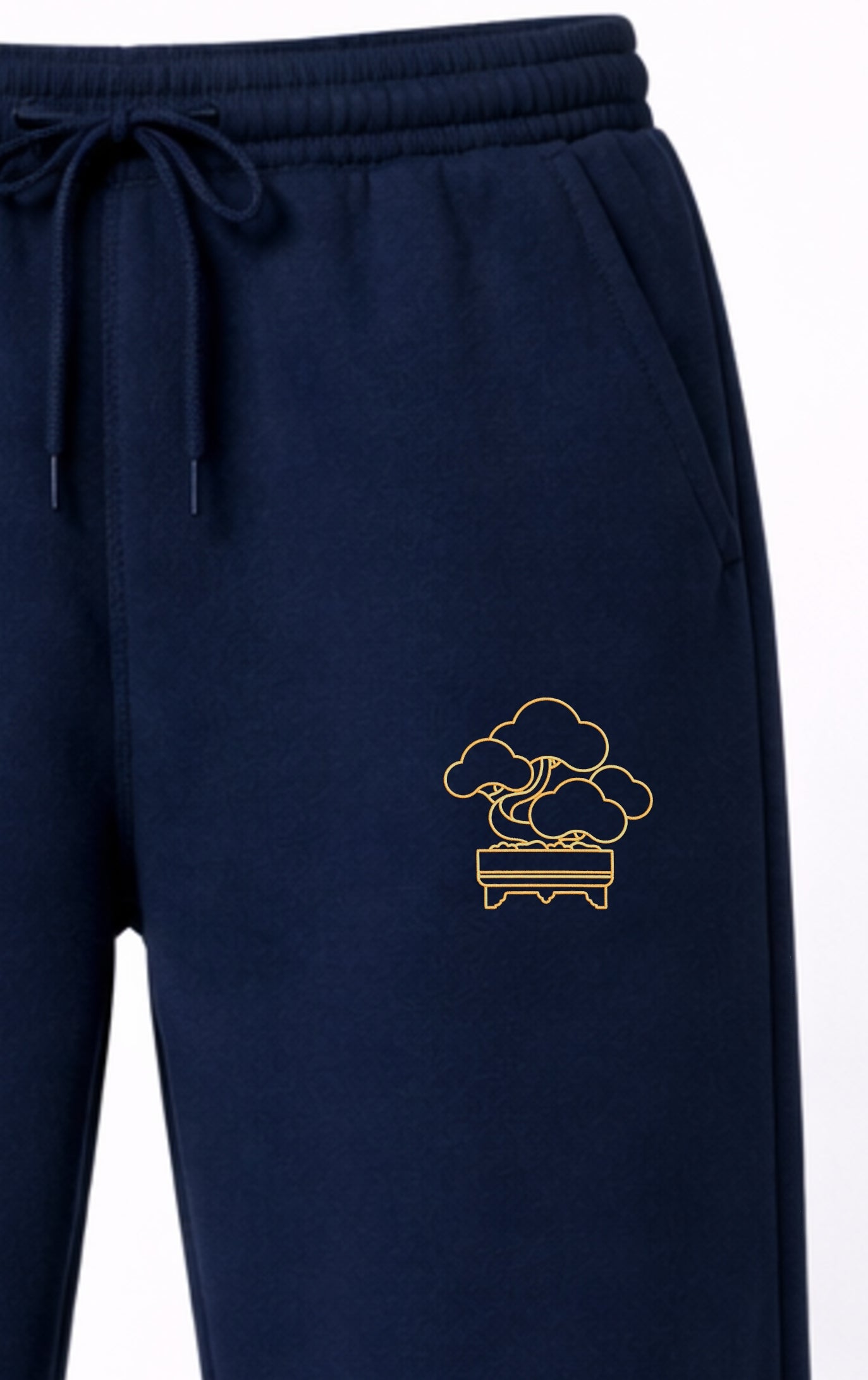 Detail shot of Andrew Joyce bespoke embroidery on 300gsm navy cotton sweatpants with Line Art Bonsai textured stitch finish.