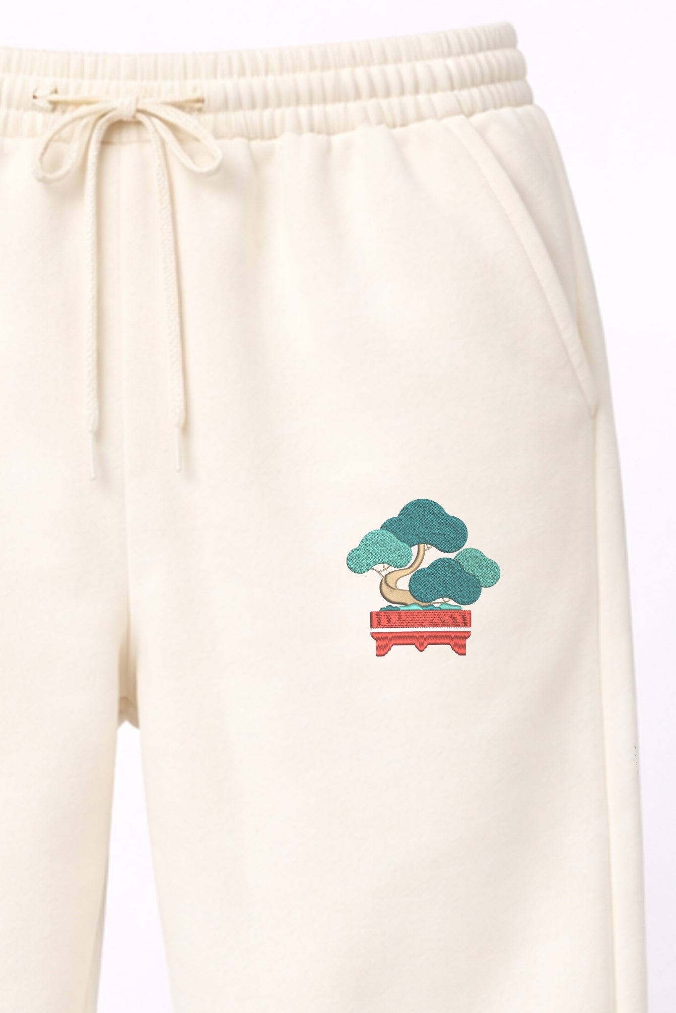 Detail shot of Andrew Joyce bespoke embroidery on 300gsm navy cotton sweatpants with Textured Art Bonsai textured stitch finish.