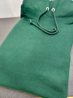 Green hoodie with a focus on the hood and drawstrings on a gray surface.