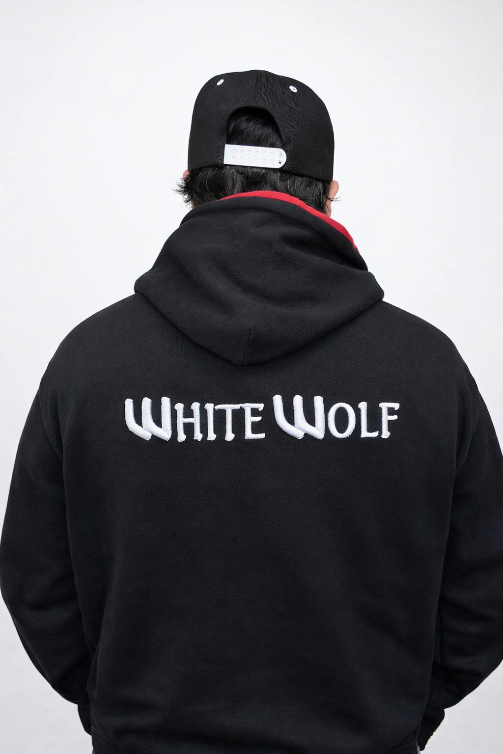 Person wearing a black hoodie with 'White Wolf' text on the back against a white background